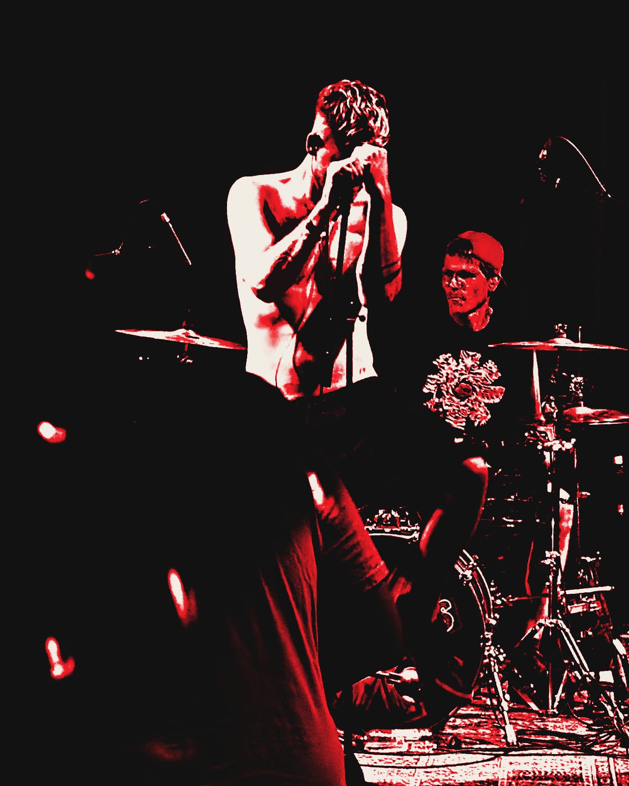 Black-and-white photo of De Peppers at Fabriek Magnifique in Veghel: Daan sings with both hands around the mic, Jan drums behind him